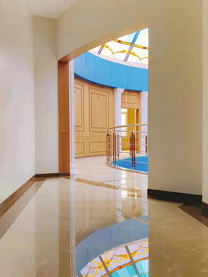 An interior view of the Arihant Aspire clubhouse, looking from a corridor into the main rotunda with its patterned floor.