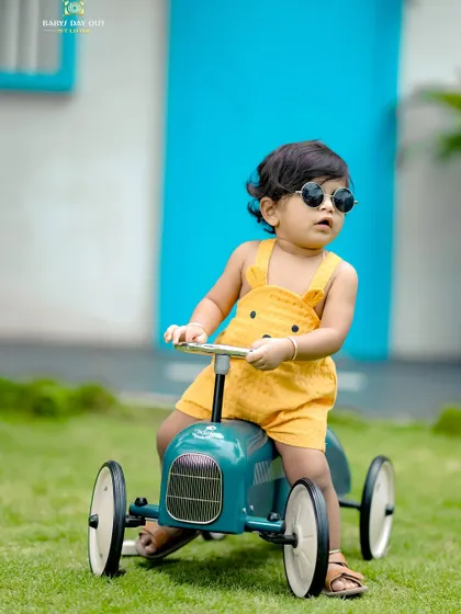 This little boy looks so cool with his sunglasses on, enjoying a ride in his toy car.