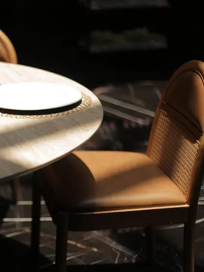 Sunlight catches the beautiful form of a Siena dining chair, highlighting its blend of tan leather and natural rattan. Our pieces are designed to be as unique as the people who gather around them.