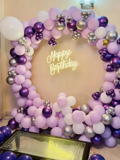 A full balloon ring in shades of purple and silver, set up in a living room.