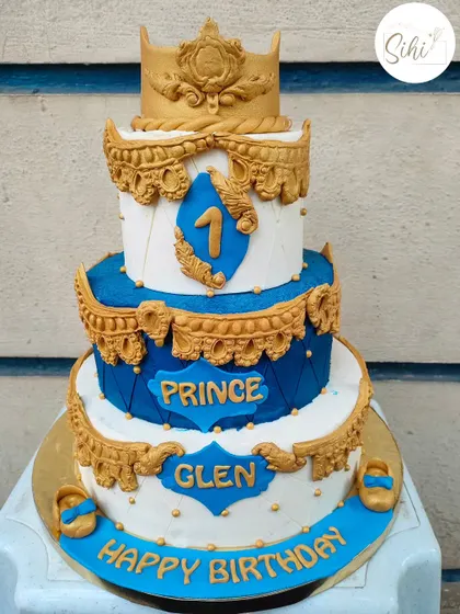 Grand birthdays call for grander cakes. This ornate three-tier prince-themed cake in royal blue and gold is perfect for a majestic first birthday celebration.