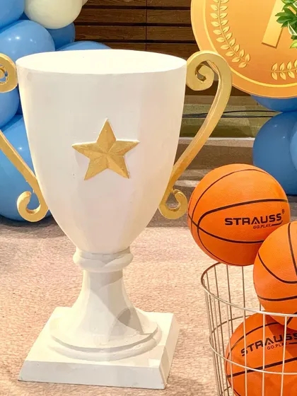 A standalone shot of our large white and gold trophy prop, which can be used as a cake table or a statement piece for any sports or achievement-themed celebration.