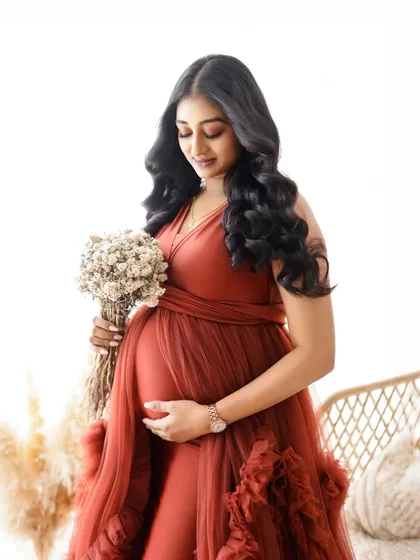 A beautiful portrait in a rich, rust-colored gown. The mom-to-be holds a bouquet of dried flowers, perfectly matching the boho-chic vibe.