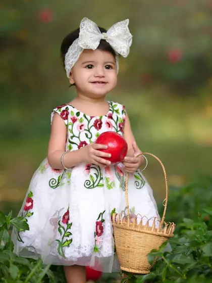 Success. She found the perfect red apple. This shot captures her sweet smile and the success of her 'apple picking' adventure during her creative baby photoshoot.