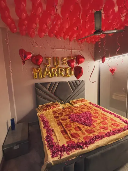 A classic 'Just Married' room decoration to welcome the newlywed couple. The ceiling is filled with red balloons, with gold foil 'Just Married' balloons on the wall. We also decorated the bed with a heart shape made from fresh rose petals for a special romantic touch.