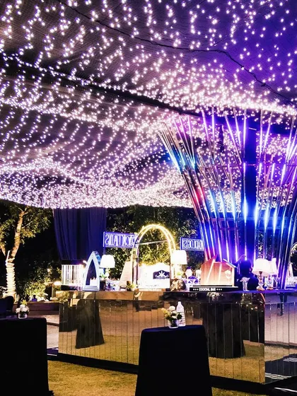 A high-energy sangeet with a canopy of fairy lights and a modern, illuminated central bar structure, designed for a night of celebration and dancing.