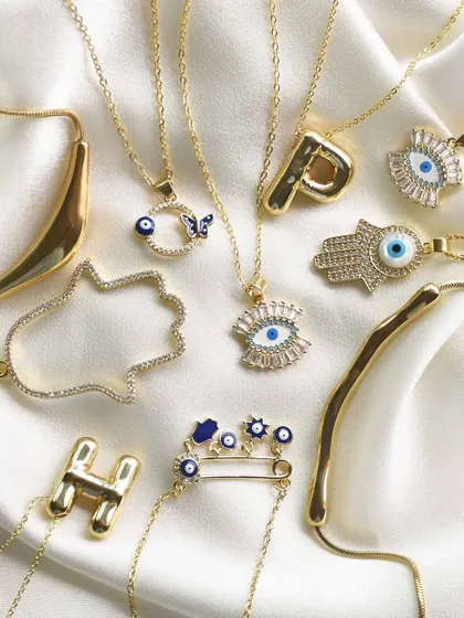 A flatlay of my favourite gold necklaces, many featuring the protective evil eye and hamsa hand. All pieces are waterproof and made with premium quality stainless steel.