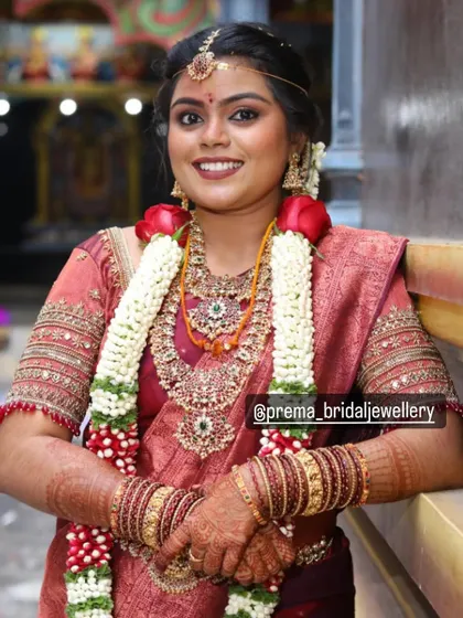 A happy bride posing for the camera in her full wedding attire and jewellery.