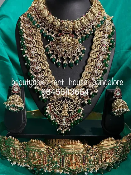 This is a grand bridal set with green beads and antique finish. The rental includes a choker with a maang tikka attached, a long haaram, and a temple vaddanam.