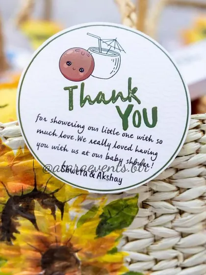 A thoughtful "Thank You" tag on a party favor from a "Coco Baby" shower. The hand-painted sunflower basket and custom tag show a personal and heartfelt appreciation for the guests.