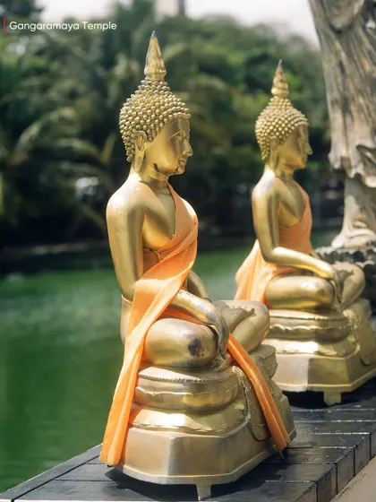Two serene, golden Buddha statues at the Gangaramaya Temple, overlooking the tranquil Beira Lake. A moment of perfect symmetry and peace.