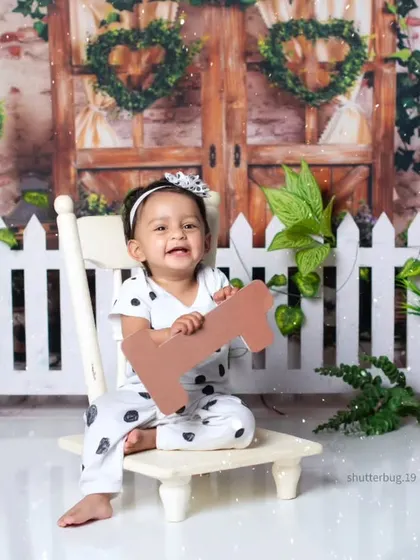 A happy baby girl holding a bone prop in our adorable panda and picket fence setup.