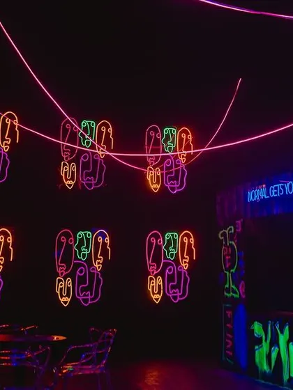 A view of the party space showing the neon signs and a graffiti art bar. We used UV paint and blacklights to make the artwork glow, adding to the underground club feel.
