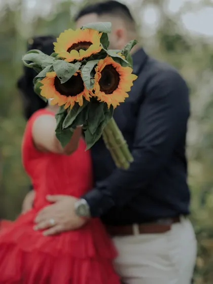 An artistic shot where the couple's embrace is partially hidden by a bouquet of sunflowers. This creative composition focuses on their connection while adding a touch of mystery and romance.