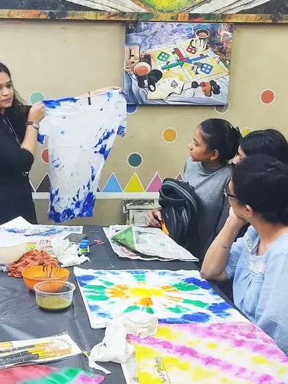An instructor demonstrating the tie-dye technique to students. This free creative session is a fun, hands-on way to learn how to create vibrant patterns on fabric.