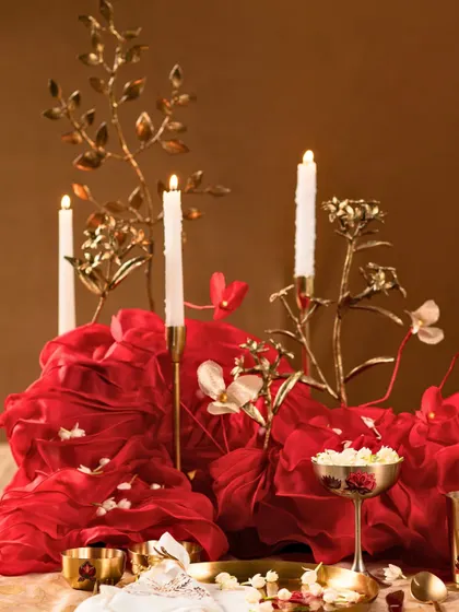 The rich red fabric centerpiece appears to flow across the table, dotted with delicate flowers and candles.