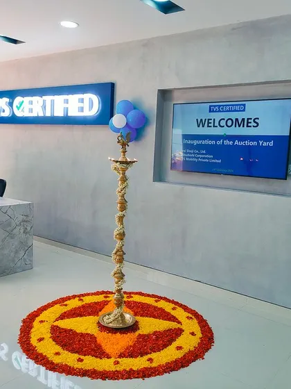 The inauguration of the TVS Auction Yard, with the reception area decorated for the opening ceremony. The design incorporates a welcome screen and traditional elements like a kuthuvilakku and pookalam, blending corporate and cultural traditions.