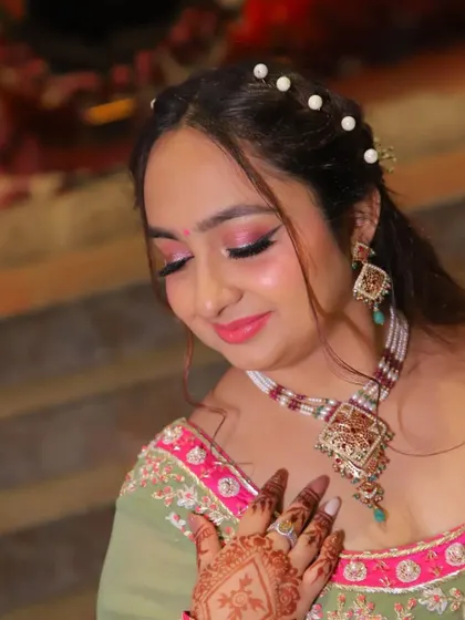 A close-up of a client's hair and makeup for an event. The half-up style with a pearl headband is a trendy and photogenic choice.