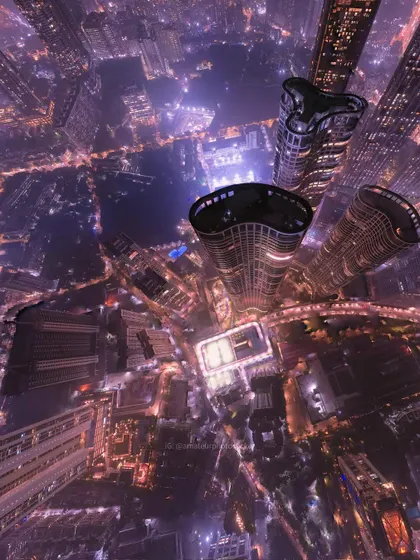 A direct top-down drone shot of Mumbai's high-rises at night. The glowing lights and unique building shapes create a captivating, abstract pattern.