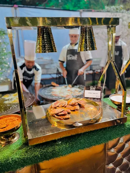The complete Surmai Tawa Fry station, with chefs cooking on a large flat-top grill.