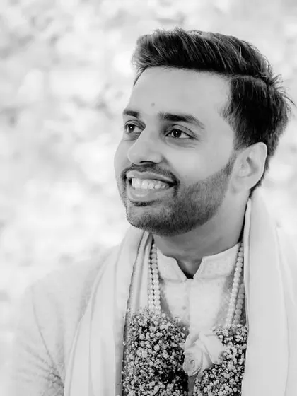 A happy, candid portrait of the groom in black and white. His genuine smile shows his excitement and joy during the wedding ceremony.