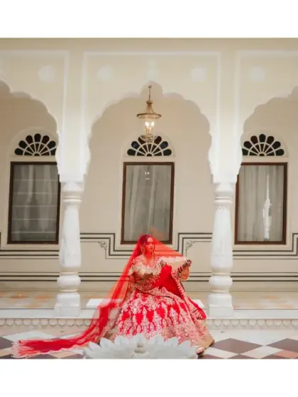 A regal portrait of the bride seated on the floor, her long red veil trailing behind her. The composition and her pose exude grace and timeless elegance.