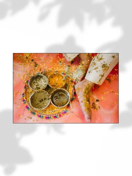A detail shot from a Haldi ceremony, showing a traditional plate with haldi paste and a foot being adorned.