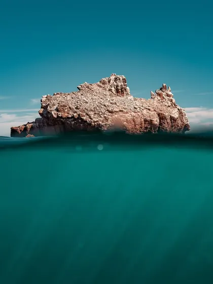 A split-level or over-under photograph showing a rocky island and the underwater world beneath it. This technique offers a unique perspective, telling the story of what's both above and below the surface in a single frame.