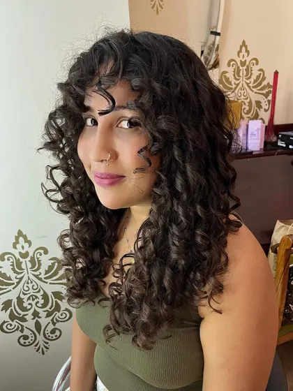 Adding shape and definition to long curly hair with layers and curly bangs.