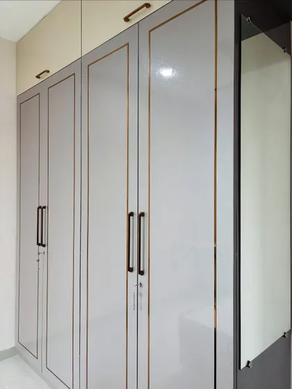 A close-up of the high-gloss laminate and the slim, modern handles chosen for this wardrobe design.