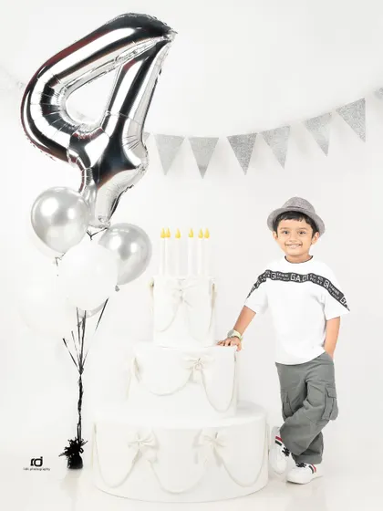 Standing proud by his birthday cake and balloons. A fourth birthday is a big deal, and this young man is ready for his portrait.