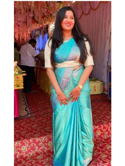 A client looking beautiful in a turquoise blue silk saree paired with a custom off-white brocade blouse and a matching embroidered belt for a defined waistline.