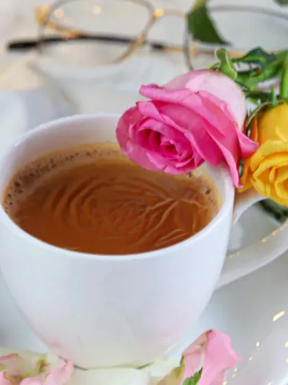 A simple, elegant shot of a cup of tea garnished with fresh roses. The close-up focus and soft lighting create a delicate and beautiful image that speaks of quiet moments.