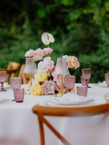 An elegant table centerpiece from the carousel party, featuring soft pink and yellow roses and unique lamp-style accents.