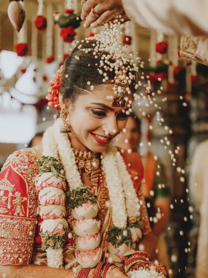 The bride's joyful smile as she is showered with Akshata rice during a key wedding ritual.