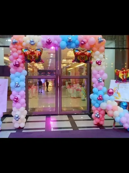 A grand entrance arch with a butterfly theme, using pastel balloons and large butterfly foil balloons to welcome guests.