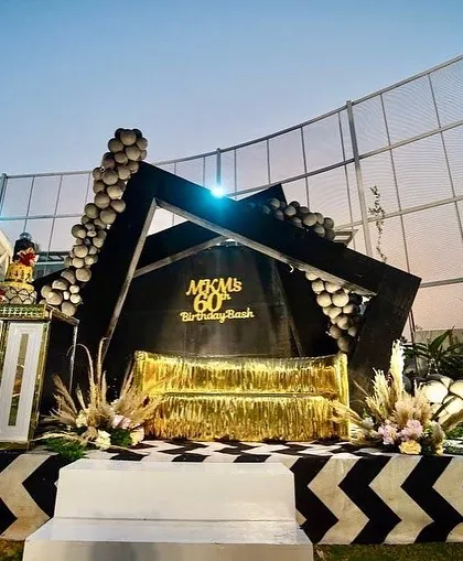 This 60th birthday bash had a chic black, gold, and white theme. The geometric stage, fringed gold sofa, and chevron-patterned floor created a sophisticated and modern look for the milestone celebration.