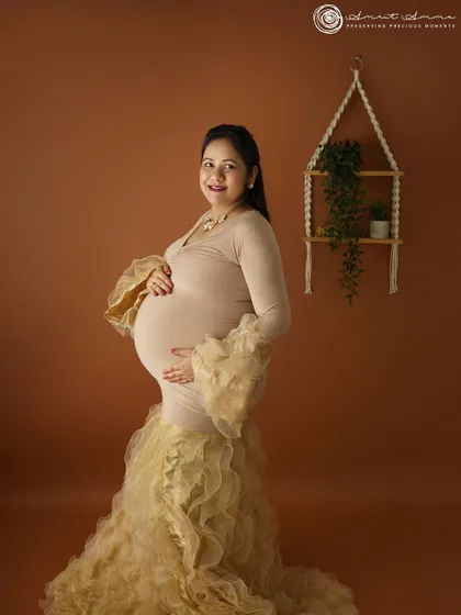 This profile shot beautifully showcases the baby bump. The simple addition of a macrame wall hanging adds a touch of boho chic to the studio setup.