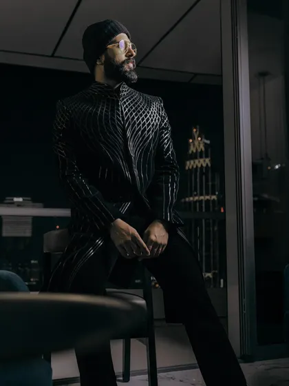 A moody, atmospheric shot of Vijay. The jacket's metallic sheen catches the low light, creating a dramatic and futuristic effect.