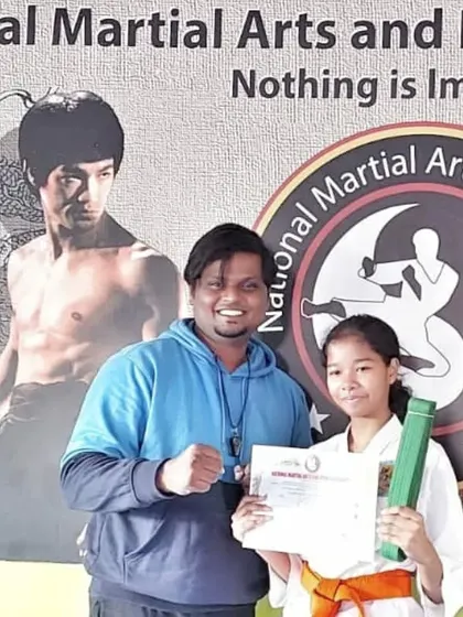 A young girl receives her orange belt, a reward for her hard work and commitment to karate.