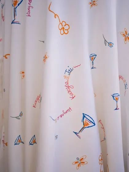 A close-up of the custom-printed fabric with playful doodles of cocktails and the couple's names, used for drapes and linens.
