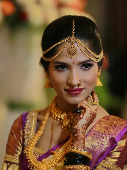 An elegant bridal portrait, with the bride's hand gently touching her face, showing off her henna and jewelry.
