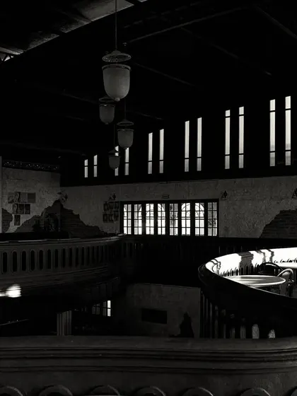 The play of light and shadow across the curved mezzanine. The high-contrast lighting creates a dramatic and moody effect.