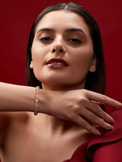 A luxurious jewelry campaign against a rich red backdrop. The pose elegantly displays a diamond bracelet, creating a look of pure sophistication.