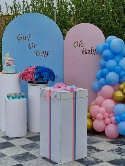 A modern 'Girl or Boy' gender reveal setup with arched backdrops, plinths, and a balloon arrangement.