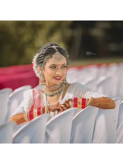 A beautiful portrait of a bride, relaxed and smiling, on her wedding day. The soft background helps her traditional white and red bangles stand out.