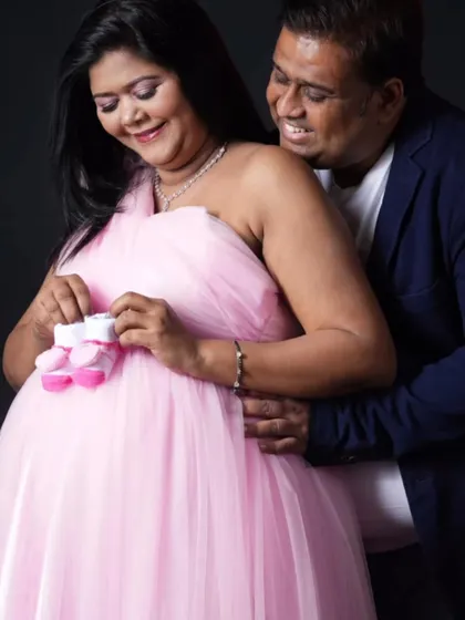 A sweet moment between the parents-to-be. The pink gown and tiny baby shoes make for a perfect maternity shoot photo.