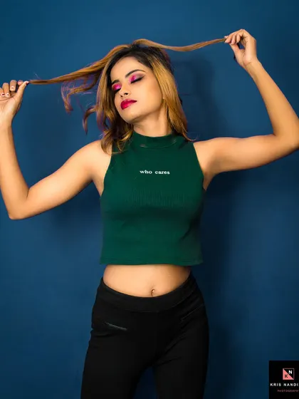 A playful and bold portrait. The model's pose, pulling at her hair, adds a dynamic and carefree energy to this studio shot, complementing the 'who cares' attitude of her top.