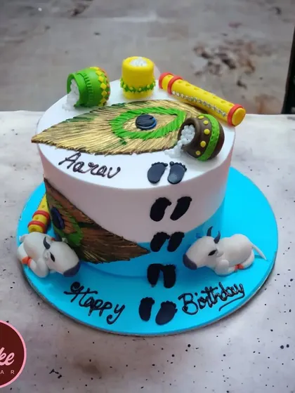 A beautiful Krishna-themed cake for a little one's birthday. It's decorated with peacock feathers, pots of butter, and tiny footprints, capturing the playful spirit of Little Krishna.