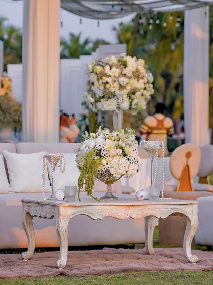 A detail of the lounge area decor, featuring a vintage-style table with a white floral arrangement and pearl necklaces used as a decorative accent. This shows our attention to small, thematic details.